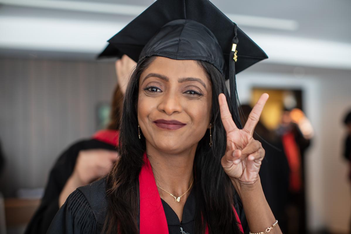 A graduating student flashes the peace sign.