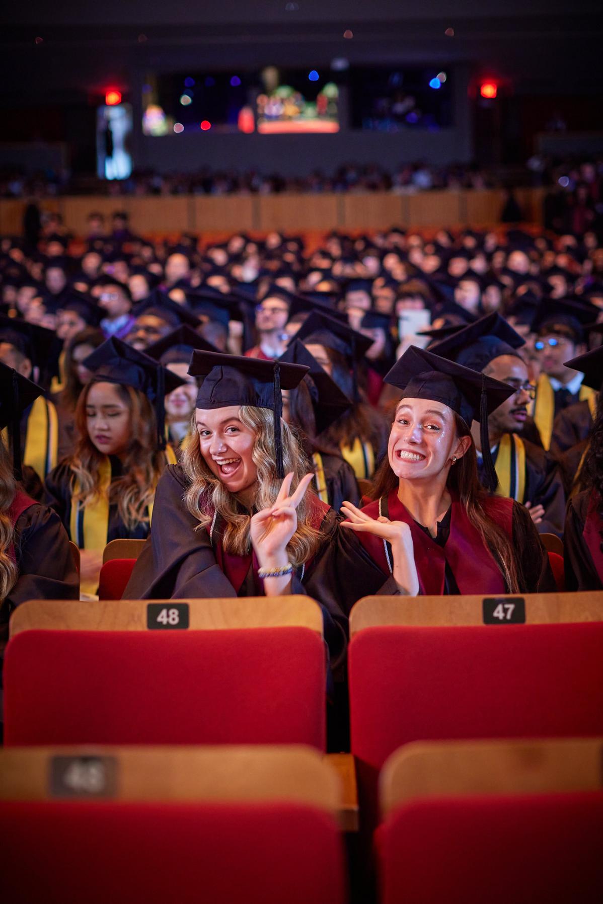 Two graduates smiling in the theatre at Convocation Ceremonies
