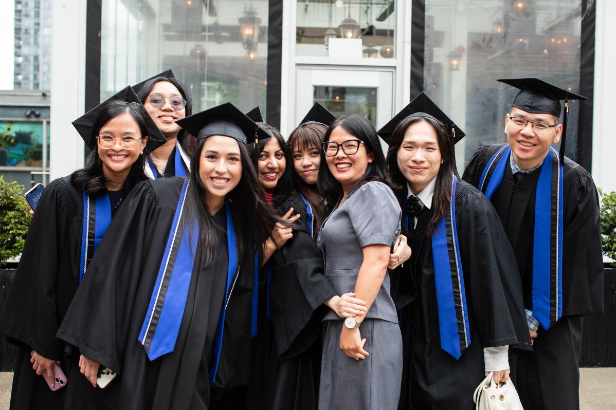 A group of graduates with a guest smiling at Convocation Ceremonies