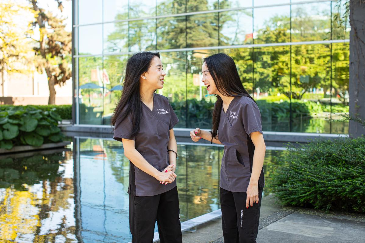 Nursing alum and sisters, Cecilia and Mandy He, share a moment outside Langar's Library Building.