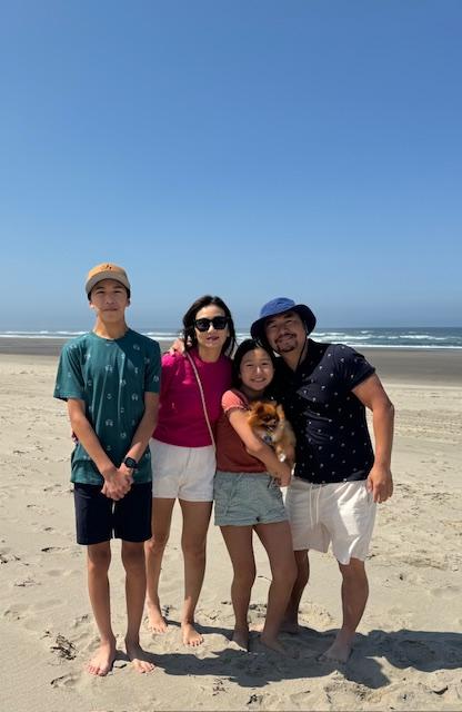 Family of four smiling and posing on a beach.