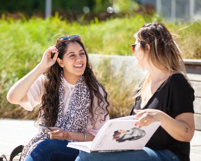 Two female-presenting students talk on Langara's main campus.