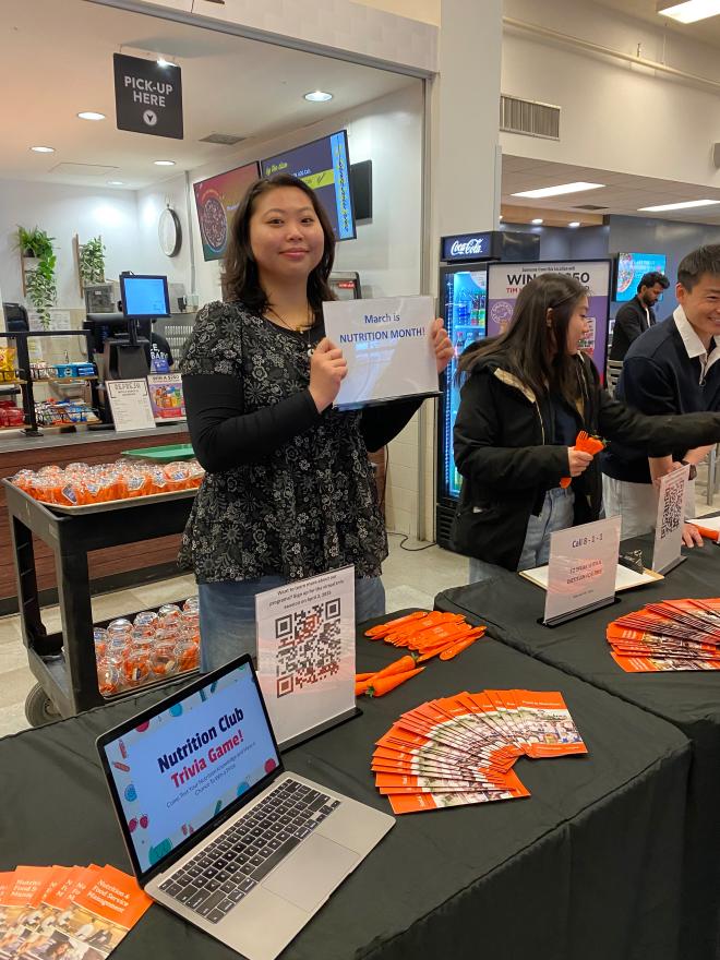 Nutrition Club president, Coco Ma, manning a booth at an on-campus event.