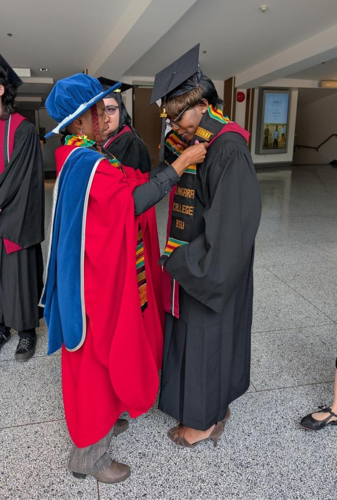Dr. Joy Walcott-Francis puts a Kente stole on a graduating student at Convocation 2026.