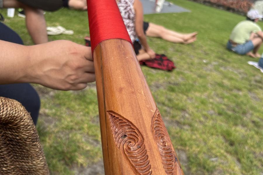 Hand holding a carved Māori item.