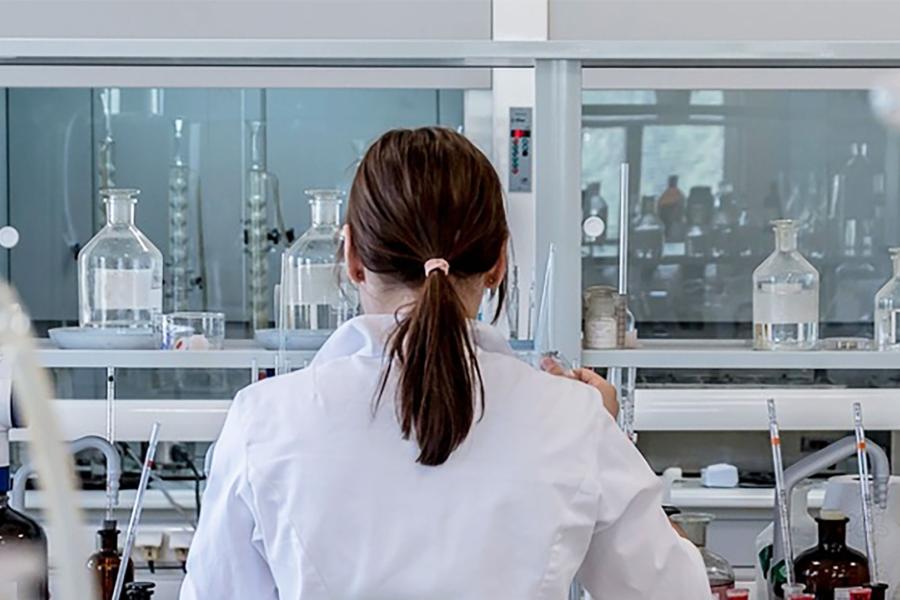A woman conducts research or technical support in a fully equipped laboratory.