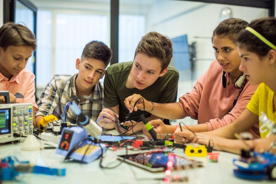 Five teens work on circuitboards to learn how they work during a summer camp session at Langara.