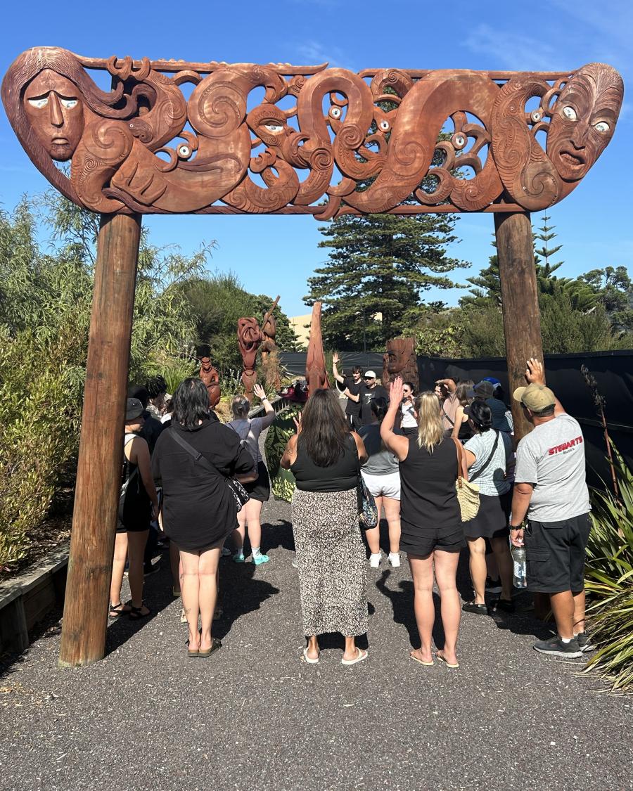 Langara delegation standing below a carved Māori gate.