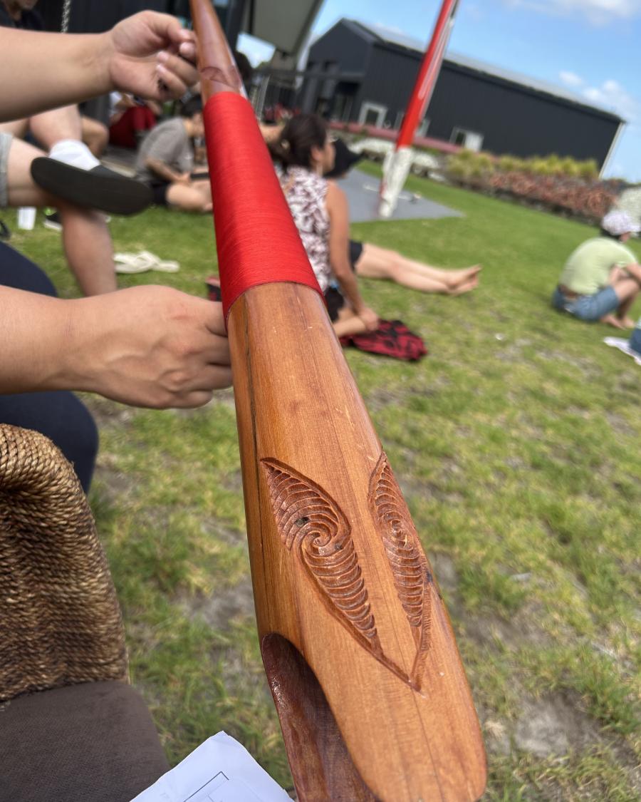 Hand holding a carved Māori item.