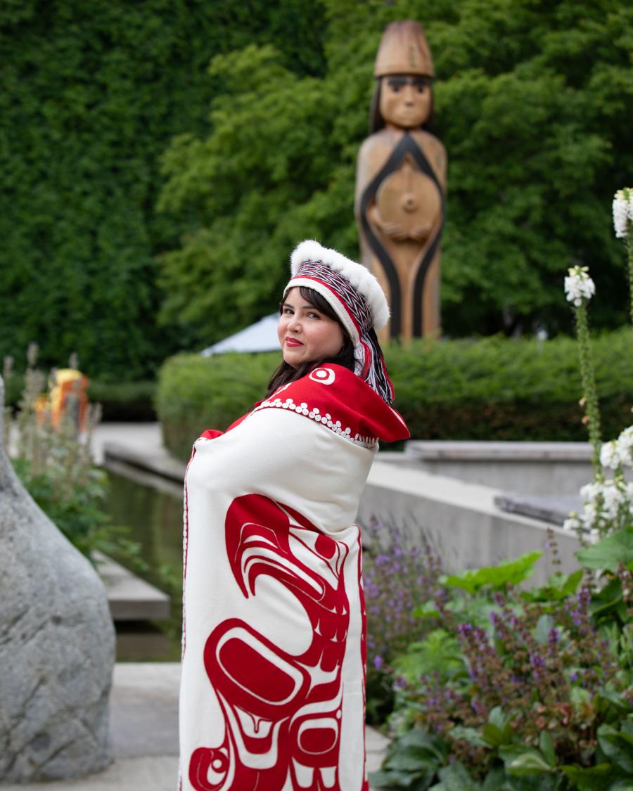 Bachelor of Science in Nursing graduate, Cecelia Simeon, wearing traditional Haida garments, posing in front of Langara College's Musqueam house post.