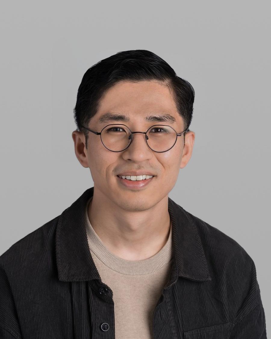 Headshot of David Alba, smiling, with round glasses and a dark jacket.